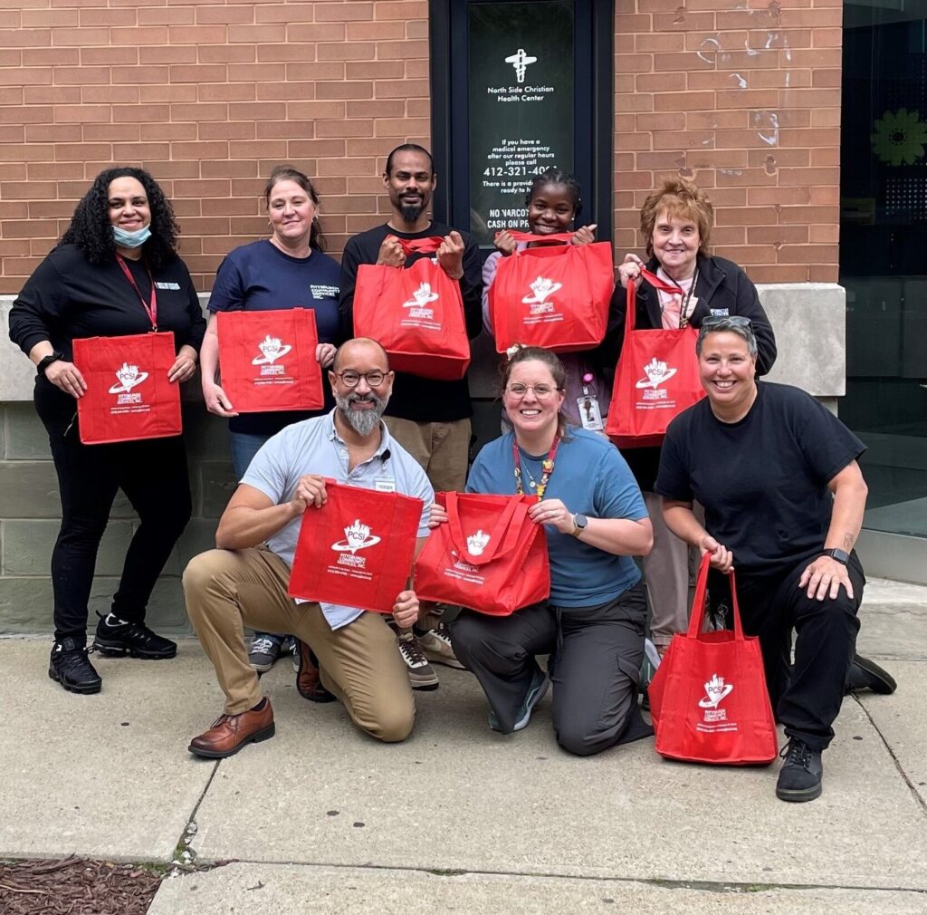 NSCHC and PCSI staff display PCSI tote bags used to distribute food
