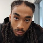 Marvin, a Black man with long braids, looks intently into the camera